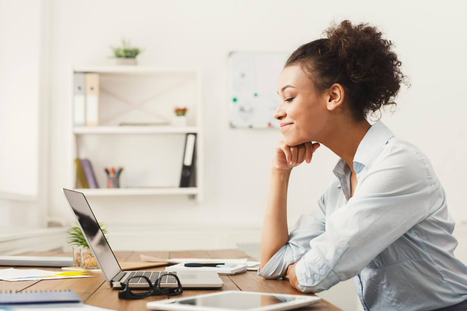 Woman at her desk smiling as she watches artificial intelligence work